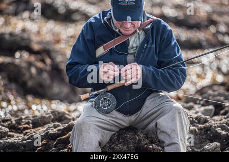 adult white male, putting a fly on his fly fishing rod Stock Photo