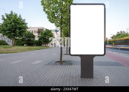 Blank Mockup Of Vertical Outdoor Poster Billboard On City Background. White Empty Advertising Lightbox On The Sidewalk Stock Photo