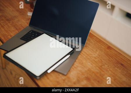 Graphics tablet placed laptop. Blank white screen mockup. Home interior wooden table. Stock Photo