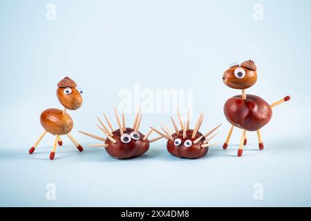 Handmade fun animals made of an natural horse chestnut and oak tree acorns. Minimalist blue studio background. Using matches and toothpicks. Stock Photo