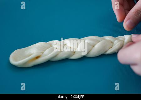 Hand shaping the dough by braiding it. Bread making process. Stock Photo