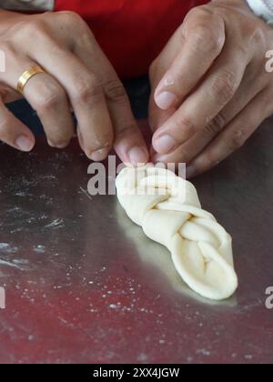 Hand shaping the dough by braiding it. Bread making process. Stock Photo