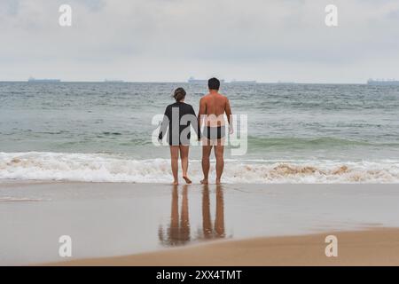 A couple holding hands in front of the sea at the Tombo beach of Guaruja, SP, Brazil. Stock Photo