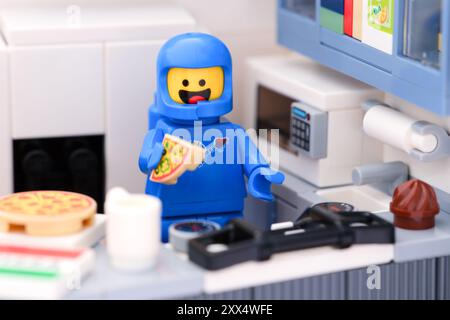 Tambov, Russian Federation - August 18, 2024 A Blue Lego astronaut minfigure eating pizza in a domestic kitchen Stock Photo