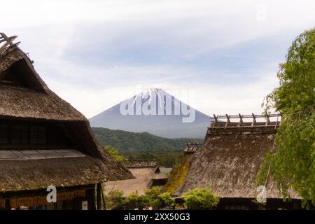 Traditional thatched-roof homes with Mt. Fuji in the background on a clear day – Yamanashi Prefecture, Japan Stock Photo