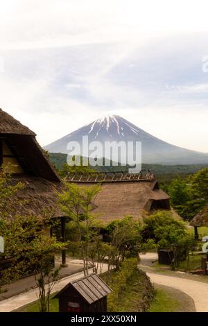 Traditional thatched-roof homes with Mt. Fuji in the background on a clear day – Yamanashi Prefecture, Japan Stock Photo