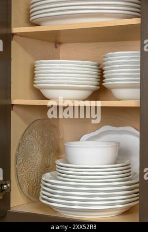 Vertical shot of clean dishes stacked neatly in a cabinet. Stock Photo