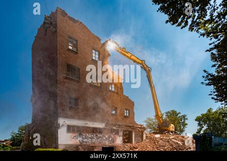 Demolition of old industrial brick structure with excavator with Hydraulic Concrete crusher tongs, demolition of former mill in Corso Savona, Asti, It Stock Photo