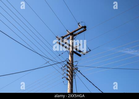 High-voltage wires on the pole three phase closeup on blue sky background Stock Photo
