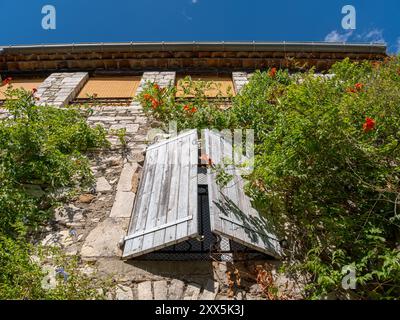 A low angle shoot of a window partly closed with blue shutters. Taken in Vezenorbes, Provence, France on a sunny August day Stock Photo