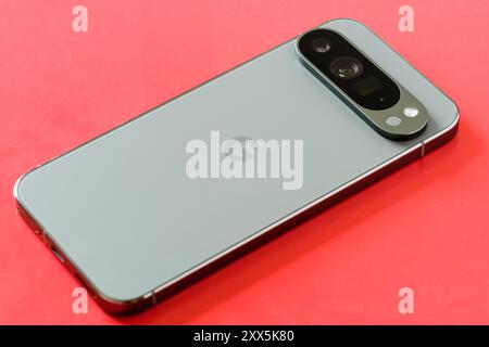Back view of the Google Pixel 9 Pro XL in Hazel Green, highlighting the triple camera on a vibrant red background, Stafford, United Kingdom, August 22 Stock Photo