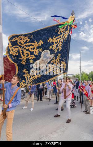 Andujar, Jaen Province, Andalusia, Spain. April 28, 2023. Men waving banners and people in traditional dress in a procession at a religious festival i Stock Photo