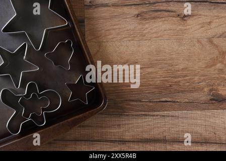 Closeup overhead view of a group of assorted cookie cutters on a baking sheet. Stars, gingerbread men and bell are shown. Stock Photo