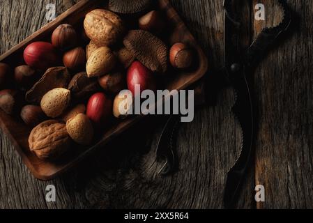 Flat lay still life of a wood dish with assorted nuts on a rustic wood table. Stock Photo