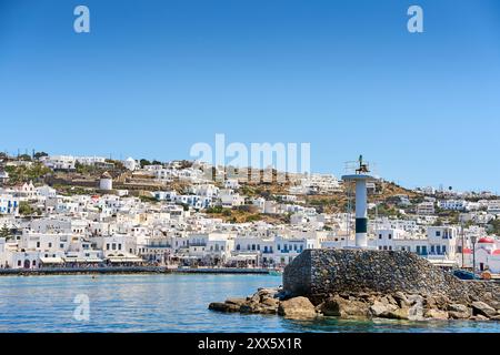 Mykonos, Greece - 7 May 2024: The town of Mykonos on the Greek island of the same name, known for its whitewashed houses and deep blue sea. View of a lighthouse in the town s old harbor *** Die Stadt Mykonos auf der gleichnamigen griechischen Insel, bekannt für ihre weiß getünchten Häuser und das tiefblaue Meer. Blick auf einen Leuchtturm im alten Hafen der Stadt Stock Photo