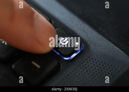 closeup of finger pushing power on button on laptop Stock Photo