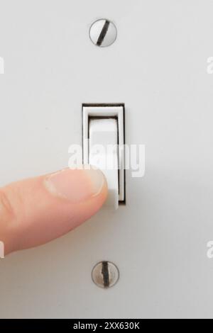 Turning lights on by flipping wall switch Stock Photo