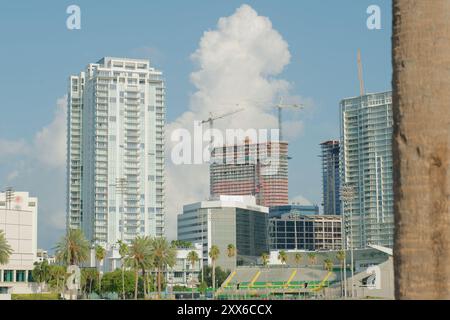 Wide shot Looking north from Demens Landing Park over bright blue water to St. Petersburg, Florida cityscape . Bright  blue and white sky. Green trees Stock Photo