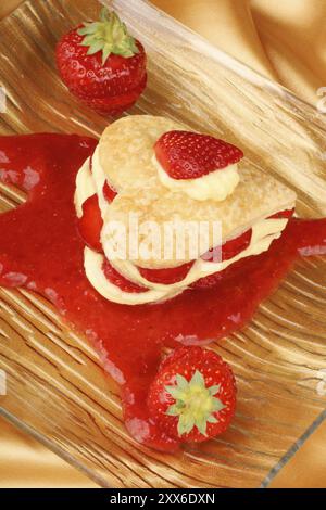 Heart shaped strawberries and custard millefeuille on strawberry sauce. For a sweet Valentine's Day. Selective focus Stock Photo