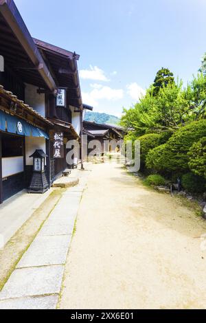 Tsumago, Japan, June 29, 2015: Rustic dirt path lined by restored traditional wooden houses on the Magome-Tsumago section of Nakasendo route on a sunn Stock Photo