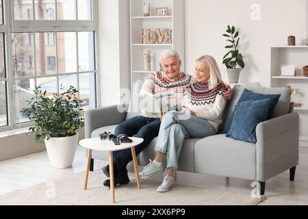 Mature couple reading magazine on sofa at home Stock Photo