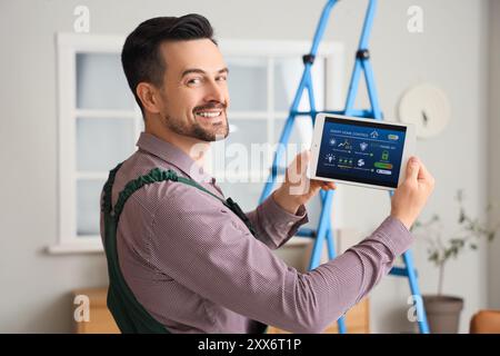 Male worker holding tablet computer with installed alarm system in room Stock Photo
