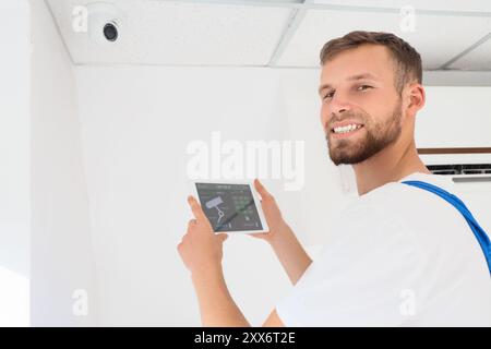 Male worker holding tablet computer with installed alarm system in room Stock Photo