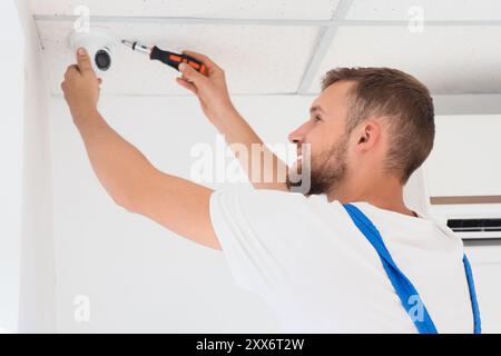 Male worker installing alarm system in room Stock Photo