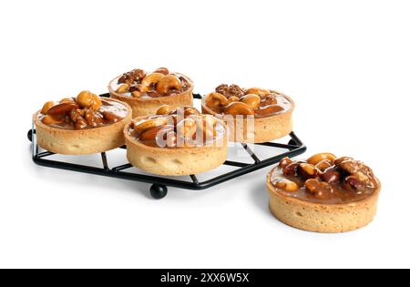 Tasty tarts with nuts and caramel on stand against white background Stock Photo
