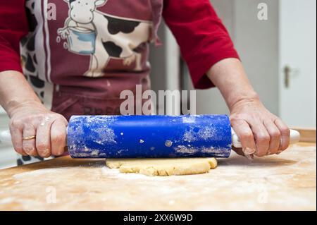 Hands guide rolling pin and roll out dough Stock Photo
