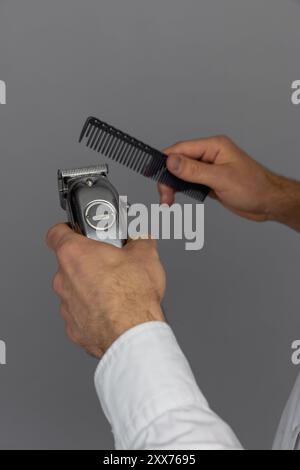 Barber holds in his hands a clipper and a comb Stock Photo