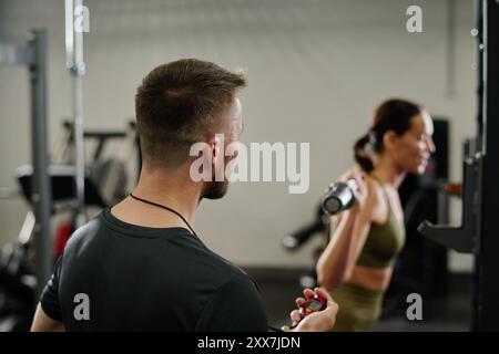 Unrecognizable trainer noting time while athlete doing squats in gym Stock Photo