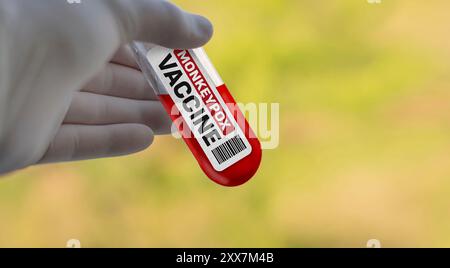 Mpox monkeypox virus vaccine. Doctor in white gloves in holding a cure for the Mpox monkeypox  virus. Selective focus of a labeled glass vial with red Stock Photo