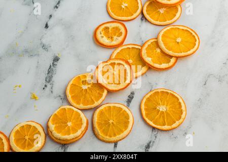 Dried orange slices on a marble surface, with zest scattered around Stock Photo