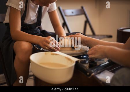 Close up woman's hands teaching girl to making pottery on a pott Stock Photo