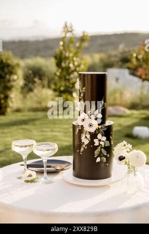Black Wedding cake decorated with flowers on small round table Stock Photo