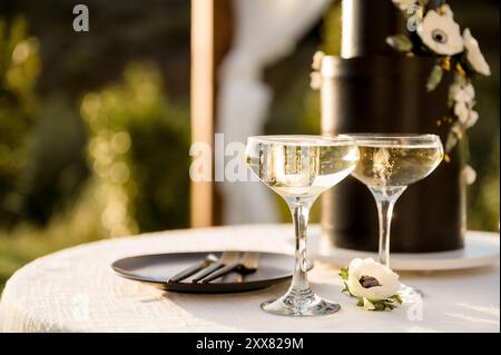 Two champagne coupes on table in front of black cake Stock Photo