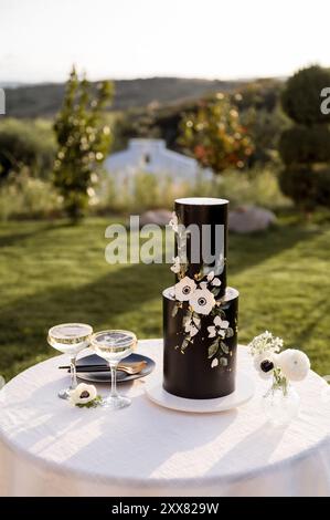 Black buttercream wedding cake on round table with champagne coupes Stock Photo