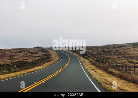 Winding rural road through open fields Stock Photo