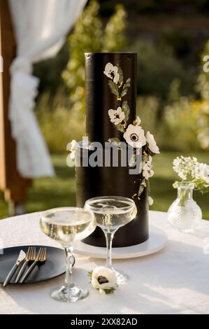 Aesthetic Black Wedding cake with white flowers and champagne Stock Photo