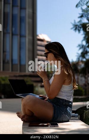 Young woman using laptop on the bench. Stock Photo