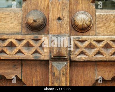 A detailed view of a highly ornate wooden door showcases intricate carvings and traditional craftsmanship, reflecting historical woodwork. Stock Photo