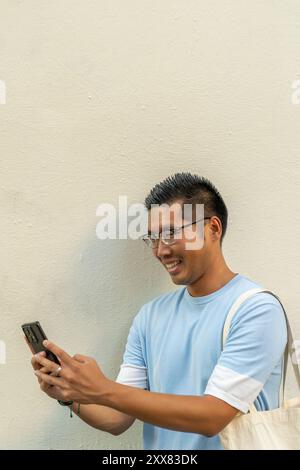 Young Asian man using his smartphone to make a video call Stock Photo