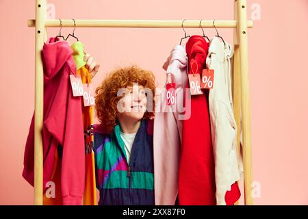 Amidst vibrant array of sale-tagged outfits, happy shopper beams with excitement, making most of markdowns on stylish finds. Concept of Black Friday Stock Photo