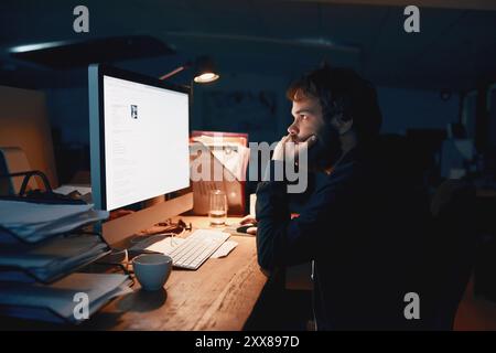 Man, programmer and night with computer, thinking and stress for glitch, screen and coding error. Person, developer and pc with monitor, reading and Stock Photo