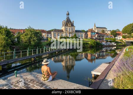 France, Somme, Valley of the Somme, Long, the banks of the Somme along the river, woman looking towards the town hall and the Saint Jean-Baptiste church Stock Photo