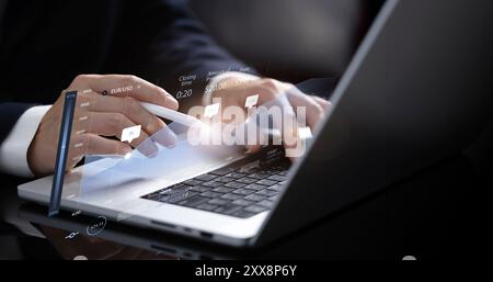 The businessman works at his laptop, where a holographic table appears displaying a graph with numerical data. Using a stylus, he interacts with the t Stock Photo