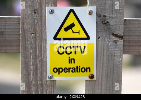 A CCTV in operation sign on a wooden fence Stock Photo