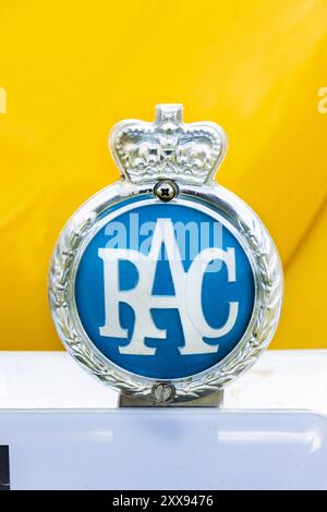 Close-up image of a historic RAC emblem with blue background and crown detail against a bright yellow background. Stock Photo