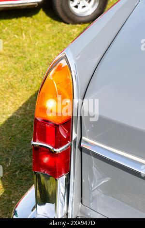 Close-up of the rear taillight of a classic gray Austin Cambridge car parked on a grassy field showcasing vintage vehicle design. Stock Photo